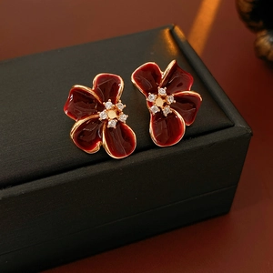 Macro shot of vintage red enamel flower earring with gold edges and zircon center