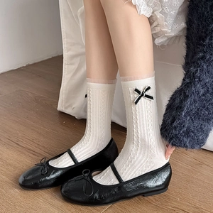 Chaussettes blanches en dentelle avec nœud noir et chaussures en cuir verni brillant