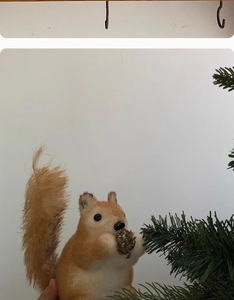 Detail of cute lifelike squirrel ornament holding a pinecone for Christmas tree decor