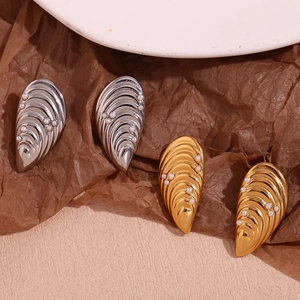 Détail de boucles d'oreilles en coquillage or et argent avec perles blanches et texture vague
