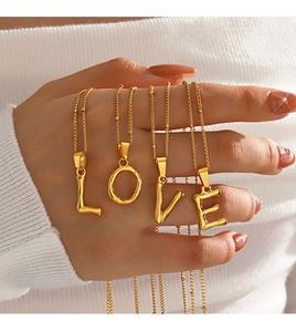 Détail de colliers alphabet dorés style bambou formant le mot LOVE tenus par un modèle