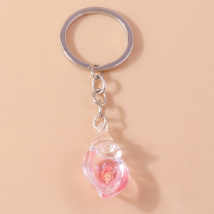 Glow-in-the-dark conch shell keychain in pink resin with silver ring on pink background