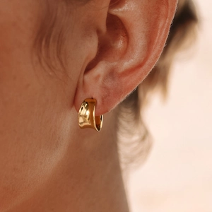 Classic golden geometric hoop earrings in titanium steel shown on a female model's ear
