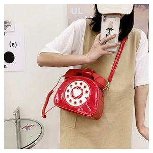 Detail of creative red patent leather crossbody bag shaped like a retro telephone