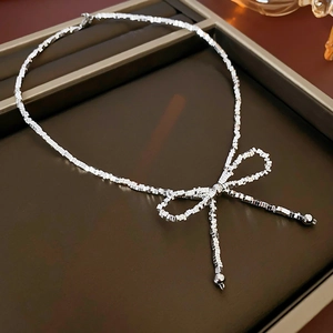 Detailed view of silver bow-knot necklace with square link chain on a display tray