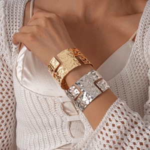 Detail of irregular geometric hammered texture on gold and silver wide open bangles