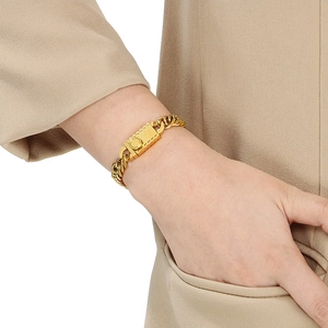 Close-up of gold titanium steel curb chain bracelet with rectangular buckle on model