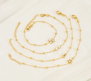 Detail of four gold plated titanium bracelets with zircon flower and butterfly charms
