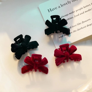 Detailed view of four small velvet bow hair clips in vibrant red and classic black colors