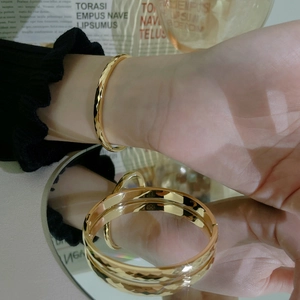 Minimalist 18K gold stainless steel bangle with diamond-cut patterns on a wrist