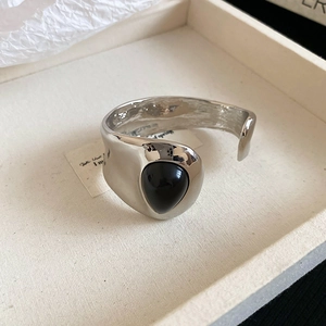 Macro shot of silver metal bangle featuring a large teardrop-shaped black gemstone inlay