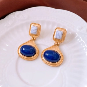 Detailed view of vintage gold earrings with blue stones on a white ceramic plate