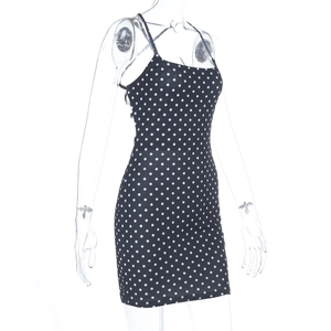 Détail de la mini-robe moulante noire à pois avec de fines bretelles sur mannequin