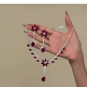 Detail of elegant teardrop flower jewelry set with red zircon stones held by hand