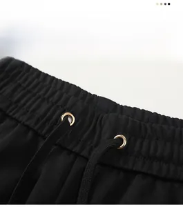 Close-up of elastic waistband with metal eyelets and flat drawstring on black joggers