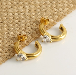 Detail of gold C-shape hoop earrings with heart-shaped zircon and butterfly backings