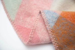 Close-up of multicolor plaid blanket scarf showing soft fabric texture and stitched edges