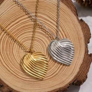 French style textured heart pendants in gold and silver finishes on a wooden base