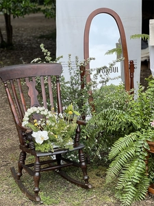 Detail of vintage dark wood rocking chair with ornate floral carving in a garden setting