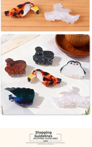 Details von Acryl-Haarklammern in Tierformen wie Koala und Pinguin auf Holzgrund