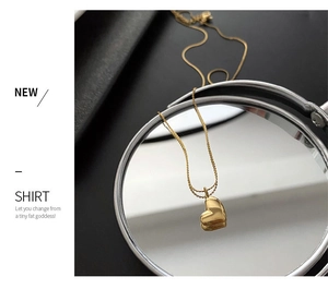 Polished gold heart pendant necklace showing reflection on a circular mirror surface