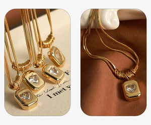Macro shot of gold square pendant with heart-shaped zircon on a snake chain necklace