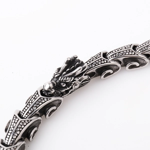 Macro view of detailed silver dragon head and scale pattern on steel chain bracelet