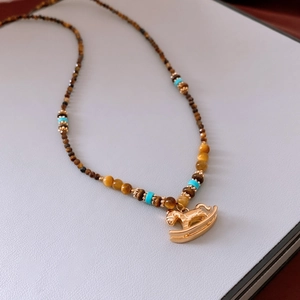 Vue détaillée du pendentif cheval à bascule plaqué or 18K avec perles en œil de tigre