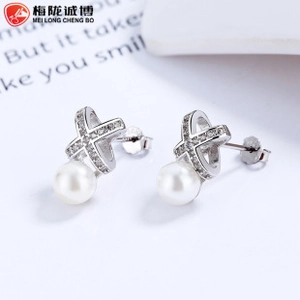 Macro view of wave silver pearl earrings with X-shaped crossover micro-paved diamonds