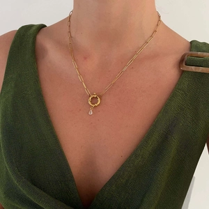 Close-up of gold paperclip chain necklace with round clasp and teardrop crystal pendant