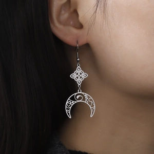 Close-up of silver crescent moon witch knot earrings worn by a model in detail view