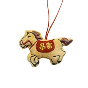 Plush yellow pony charm with red saddle featuring gold Chinese embroidery on white background