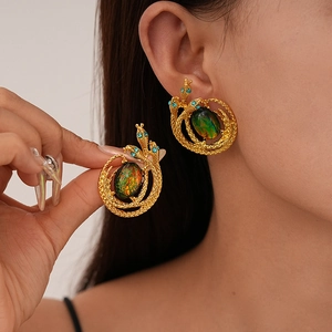 Detail of vintage snake earrings with green-orange faux gem and blue rhinestone eyes