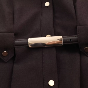 Détail d'une robe chemise marron foncé avec boucle de ceinture dorée et boutons en métal