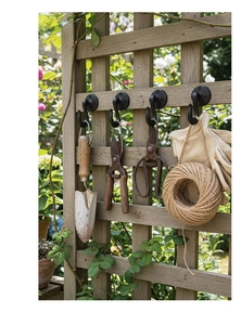Retro iron wall hooks installed on wood showing garden tools and heavy-duty metal texture