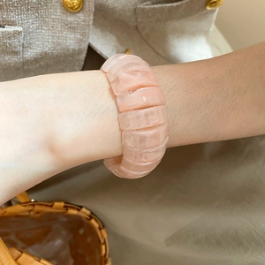 Detailed view of pink resin elastic bracelet with block texture on a woman's wrist