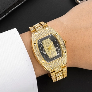 Macro shot of gold tonneau watch set with crystals on wrist with a black hollow dial