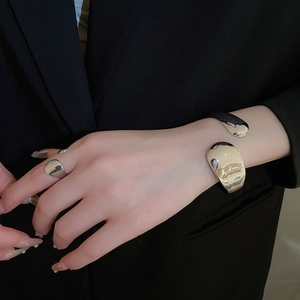 Detailed view of polished silver metal oval open bangle and matching ring on model