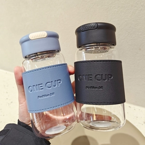 Detail view of portable glass cups with blue and black leather sleeves and tea strainers