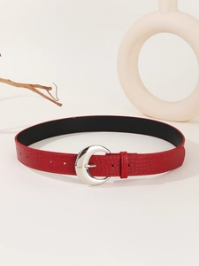Close-up of red crocodile-patterned belt with silver C-shaped metal buckle on beige background