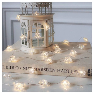 Close-up of warm white LED star string lights on a white iron lamp stand and books