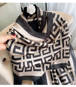 Macro shot of houndstooth silk scarf showing soft texture and premium drape on chair