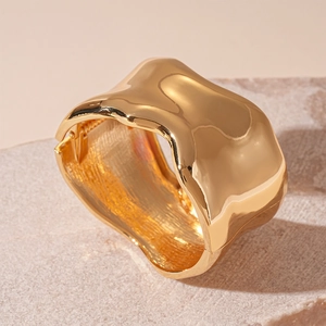 Close-up of gold organic irregular wide cuff bracelet on a natural stone base