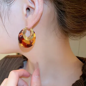 Detail of round acetate tortoiseshell hoop earrings with gold sunburst metal inlay