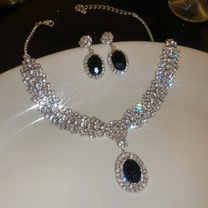 Detailed close-up of oval black gemstone necklace and earrings set with crystal pavé halo