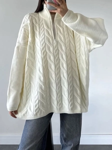 Detailed close-up of white cable-knit texture and half-zipper collar on this warm sweater