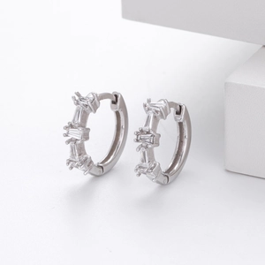 Close-up of silver hoop earrings with channel-set baguette cut crystals on white base