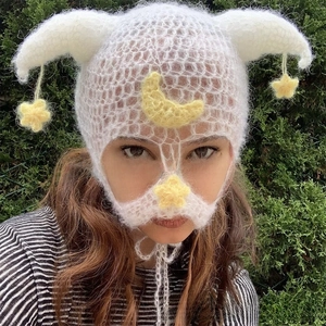 Detail of white crochet balaclava with devil horns and yellow moon star patches