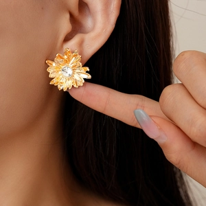 Vintage gold daisy earrings with crystal center and brushed texture petals shown on ear