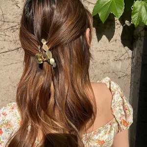Detail of opal claw clip on hair with elegant gold alloy finish and cream oval stones